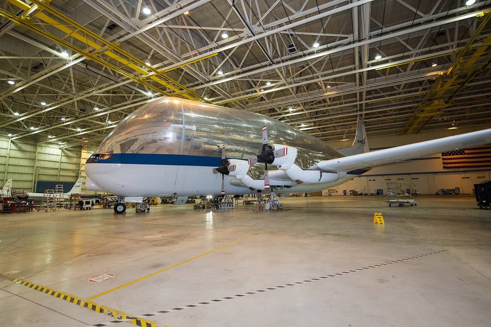 A NASA cargo aircraft parked inside a large, brightly lit hangar